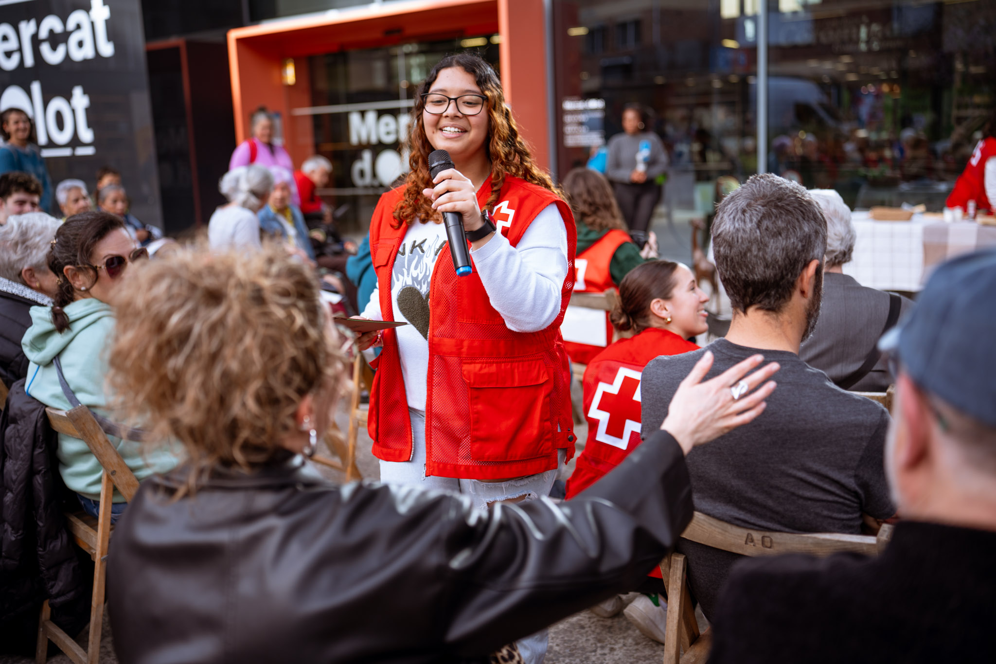 Fotografía corporativa — voluntària de Creu Roja parlant amb micròfon en acte al carrer